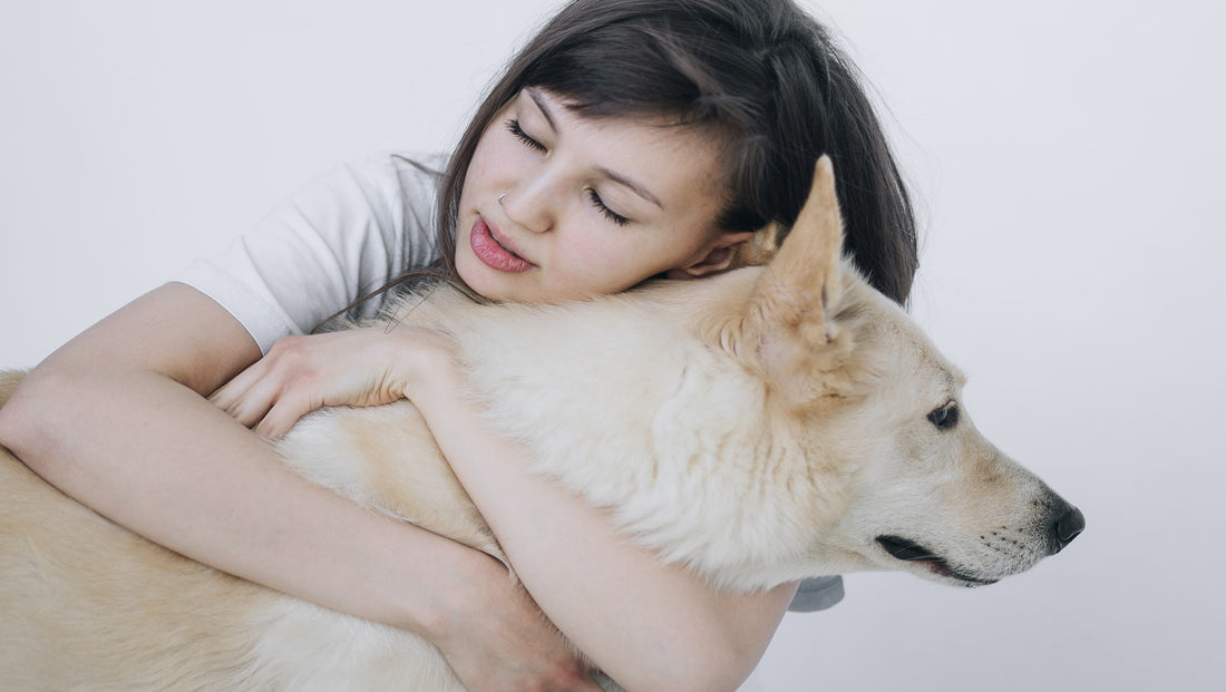A young woman hugs a white dog